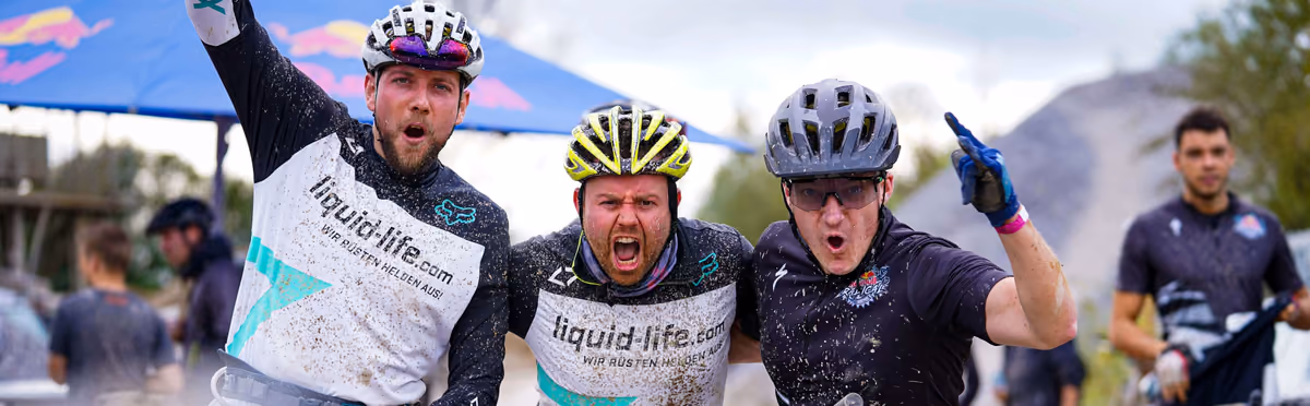 Die drei Geschäftsführer von Liquid-Life jubeln voller Schlamm nach einer Mountainbike-Tour